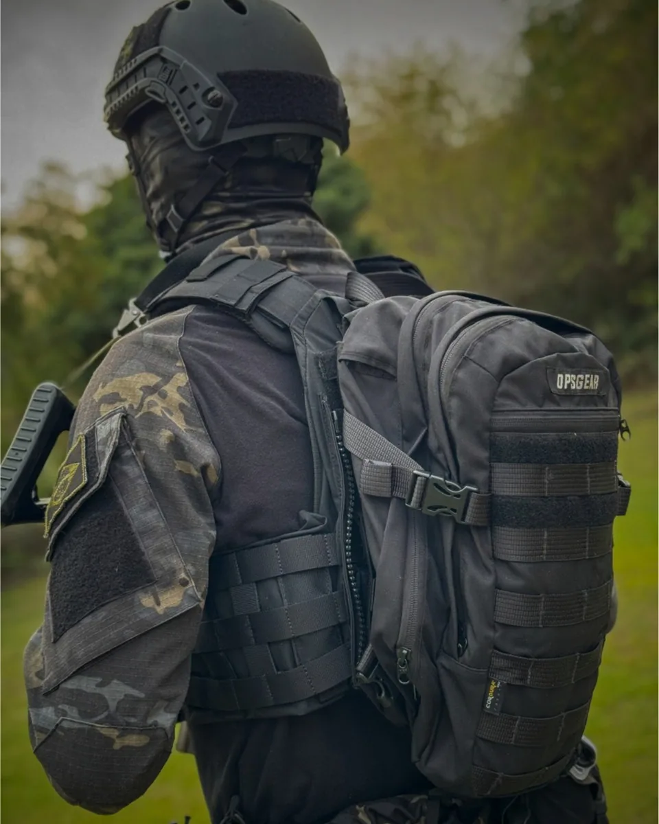 Operador de costas usando mochila tática preta OPSGEAR sobre colete